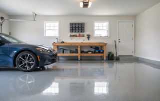 Blue car parked in a clean garage with a wooden workbench and shiny epoxy floor.