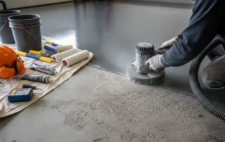 Professional concrete grinding for epoxy floor preparation, featuring a digital moisture meter and coating tools to ensure proper bonding in Virginia garages.